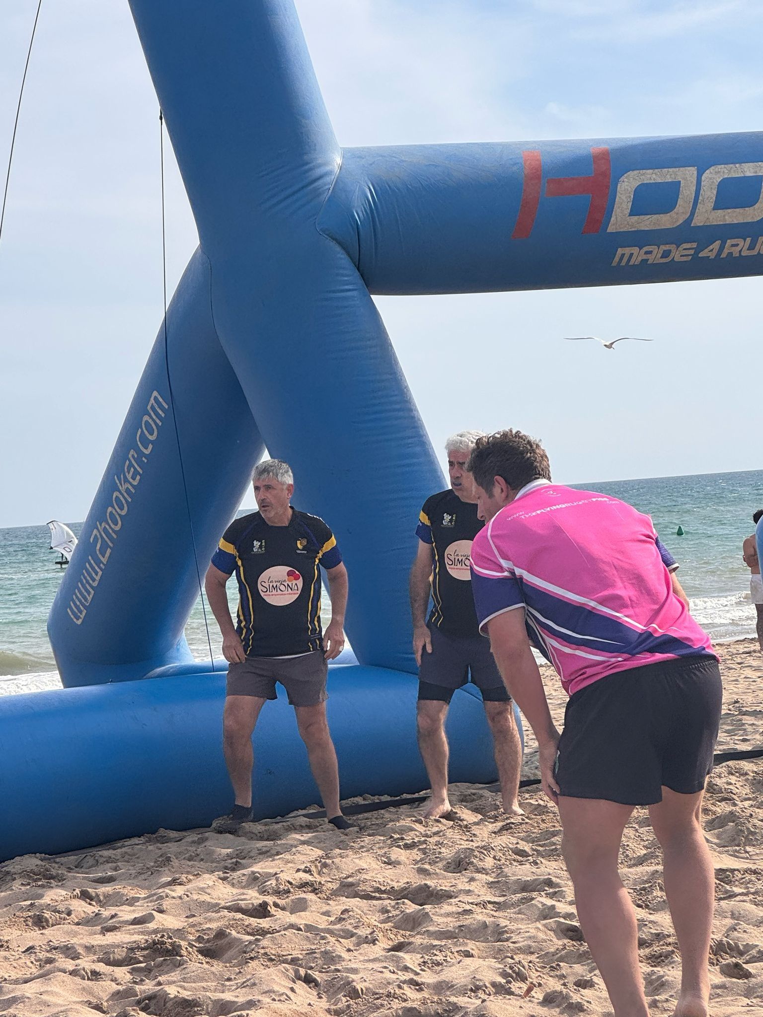 Un jugador amb la samarreta rosa dels Flying Rugby Pigs davant dels pals inflables i el mar